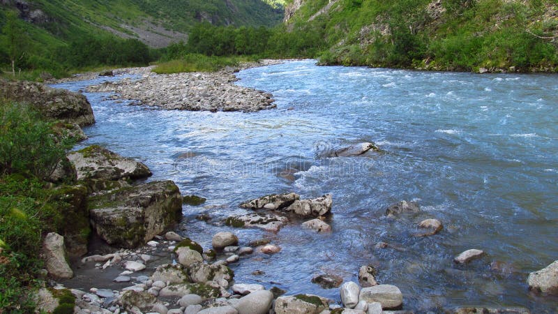 Härligt blått vatten i floden i den gröna vallen arkivfoto Härligt blått vatten i floden i den gröna vallen arkivfoto