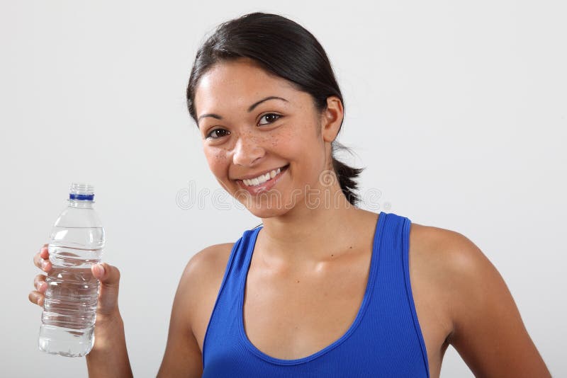 Close up of young athletic woman with beautiful smile wearing blue exercise vest holding bottled water - Canon 5D MKII. Close up of young athletic woman with beautiful smile wearing blue exercise vest holding bottled water - Canon 5D MKII