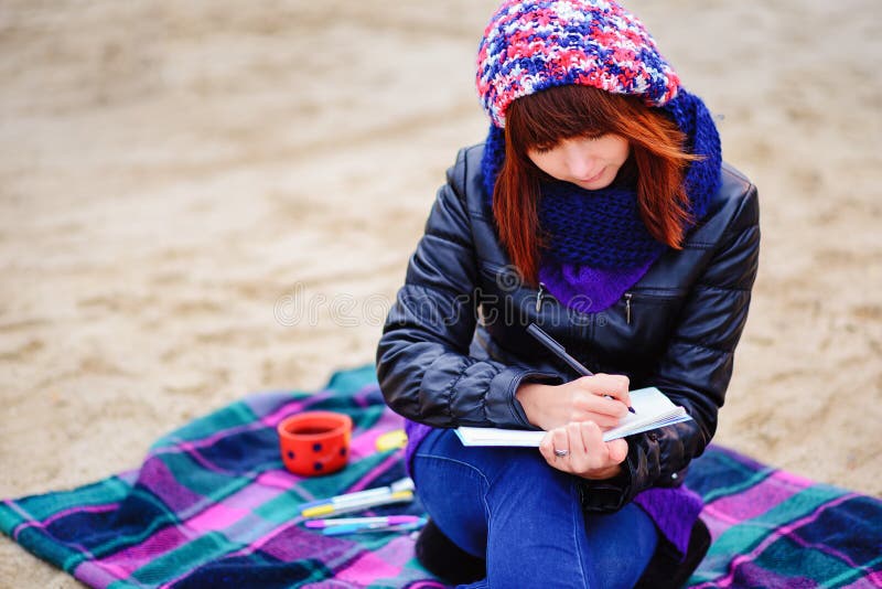 Härligt flickasammanträde på stranden och har rekord i en noteboo arkivfoto Härligt flickasammanträde på stranden och har rekord i en noteboo arkivfoto
