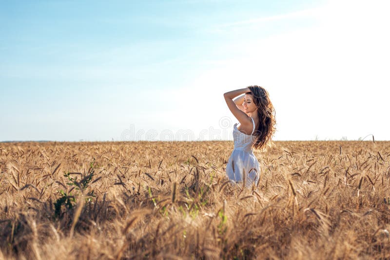 Härligt lyckligt kvinnafält, solig eftermiddag, vit klänning Brunetthår, garvad hud, begrepp av att tycka om naturen Lyckligt royaltyfri fotografi Härligt lyckligt kvinnafält, solig eftermiddag, vit klänning Brunetthår, garvad hud, begrepp av att tycka om naturen Lyckligt royaltyfri fotografi