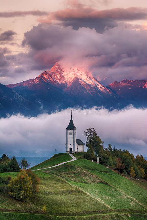 Härligt soluppgånglandskap av kyrkliga Jamnik i Slovenien med molnig himmel arkivfoto Härligt soluppgånglandskap av kyrkliga Jamnik i Slovenien med molnig himmel arkivfoto