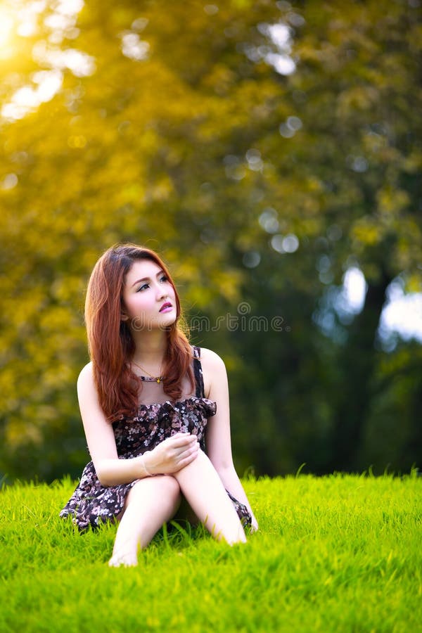 Härligt ungt asiatiskt kvinnasammanträde på grönt gräs