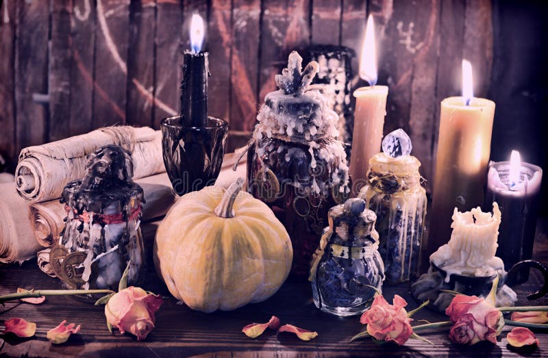 Witch bottles with pumpkin, black candles and paper scrolls. Wicca, esoteric, Halloween and occult background with vintage magic objects for mystic rituals. Witch bottles with pumpkin, black candles and paper scrolls. Wicca, esoteric, Halloween and occult background with vintage magic objects for mystic rituals