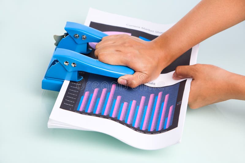 Employee's hand is pressing hole puncher where the documents placed in. Taken from side view. Employee's hand is pressing hole puncher where the documents placed in. Taken from side view.