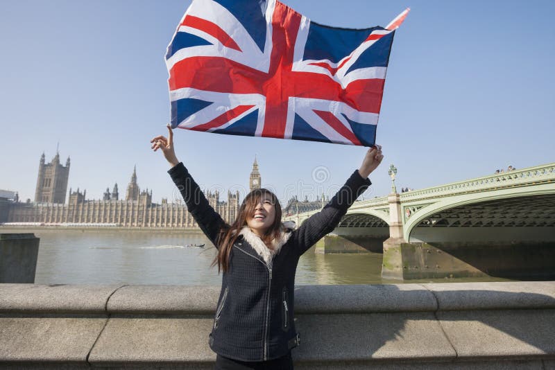 Happy woman holding British flag while standing against Big Ben at London, England, UK. Happy woman holding British flag while standing against Big Ben at London, England, UK