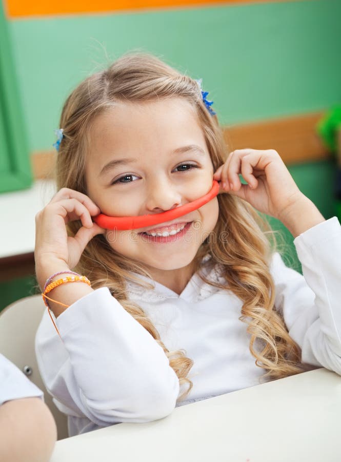 Hållande mustasch för flicka som göras av Clay In Preschool royaltyfria foton Hållande mustasch för flicka som göras av Clay In Preschool royaltyfria foton