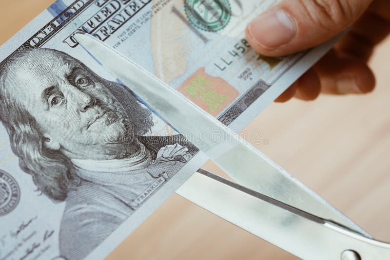 Hållande sax för kvinnahand som klipper US dollarsedlar, snittknopp arkivbilder Hållande sax för kvinnahand som klipper US dollarsedlar, snittknopp arkivbilder