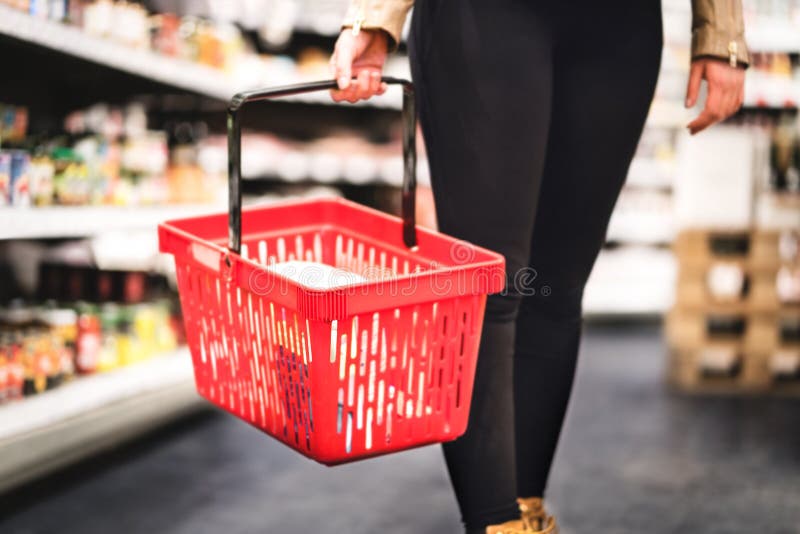 Hållande shoppingkorg för kvinna och gå i livsmedelsbutikgång
