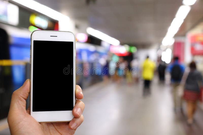 Hållande smartphone för hand med bakgrund för gångtunnelstation fotografering för bildbyråer Hållande smartphone för hand med bakgrund för gångtunnelstation fotografering för bildbyråer