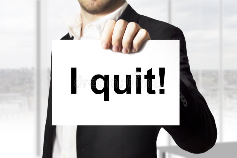 Businessman in office holding sign i quit. Businessman in office holding sign i quit