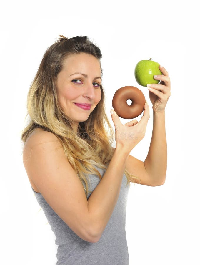 Hållande äpple för attraktiv kvinna och chokladmunk i sund söt skräpmatfrestelse för frukt kontra fotografering för bildbyråer Hållande äpple för attraktiv kvinna och chokladmunk i sund söt skräpmatfrestelse för frukt kontra fotografering för bildbyråer