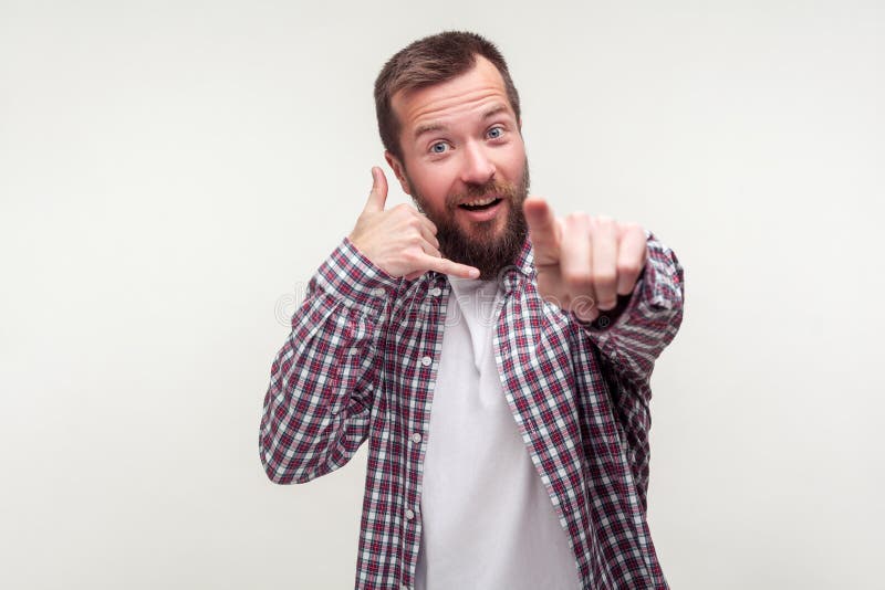 Hé vous m'appelez de retour! Portrait de l'homme barbu positif vers la caméra et faisant le geste de téléphone. Fond blanc images stock