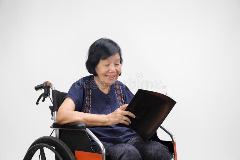 Hög asiatisk kvinna som ler, medan läsa tidskriften fotografering för bildbyråer Hög asiatisk kvinna som ler, medan läsa tidskriften fotografering för bildbyråer