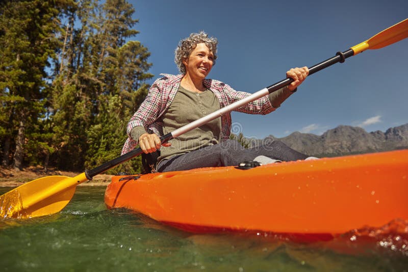 Portrait of senior woman paddling in a lake. Happy mature caucasian woman canoeing on summer day. Portrait of senior woman paddling in a lake. Happy mature caucasian woman canoeing on summer day.