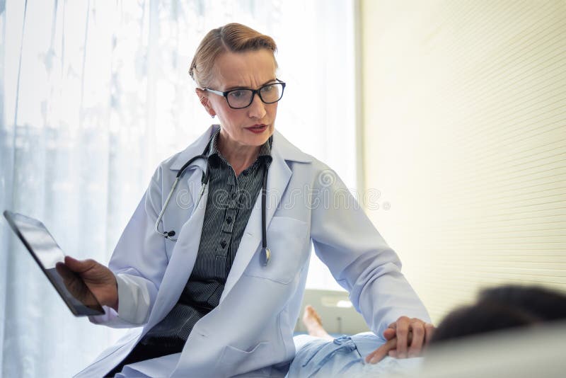Hög kvinnadoktor som uppmuntrar hennes kvinnliga patient arkivfoto Hög kvinnadoktor som uppmuntrar hennes kvinnliga patient arkivfoto