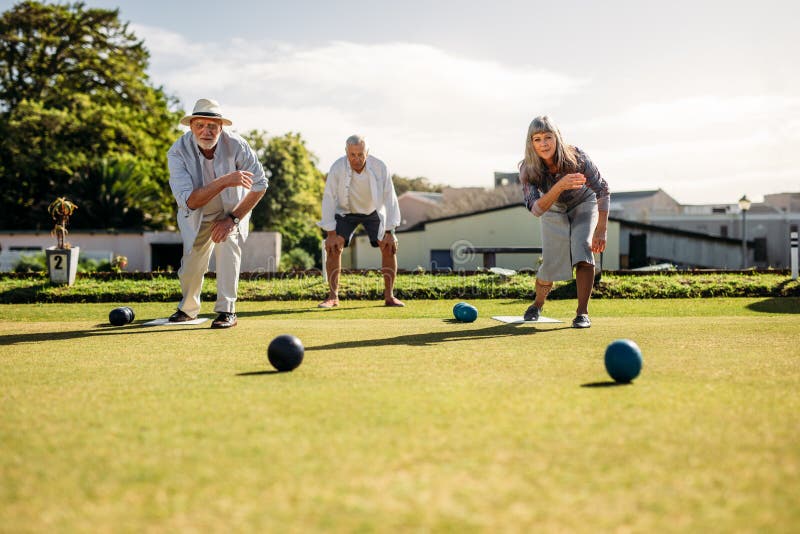 Hög man och kvinna som spelar boules i en gräsmatta fotografering för bildbyråer Hög man och kvinna som spelar boules i en gräsmatta fotografering för bildbyråer
