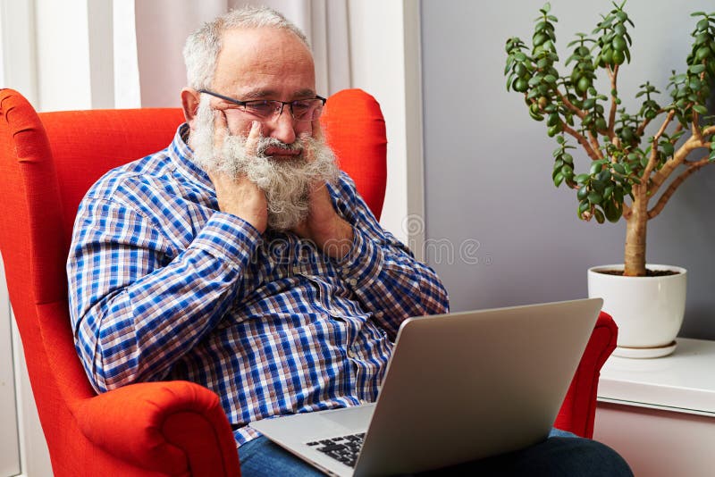 Hög man som hemma ser bärbara datorn och borrning fotografering för bildbyråer Hög man som hemma ser bärbara datorn och borrning fotografering för bildbyråer