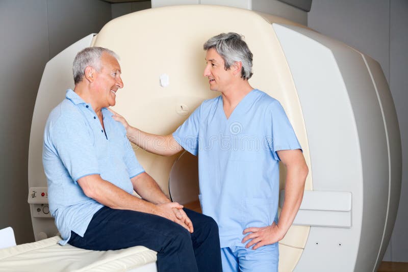 Mature male radiologic technician comforting senior patient before MRI scan. Mature male radiologic technician comforting senior patient before MRI scan