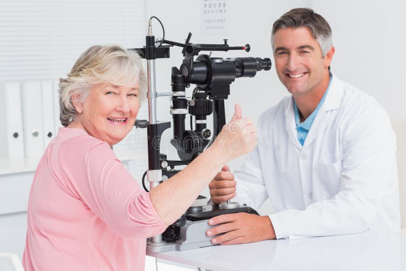 Hög patient som gör en gest upp tummar, medan sitta med optiker arkivbilder Hög patient som gör en gest upp tummar, medan sitta med optiker arkivbilder