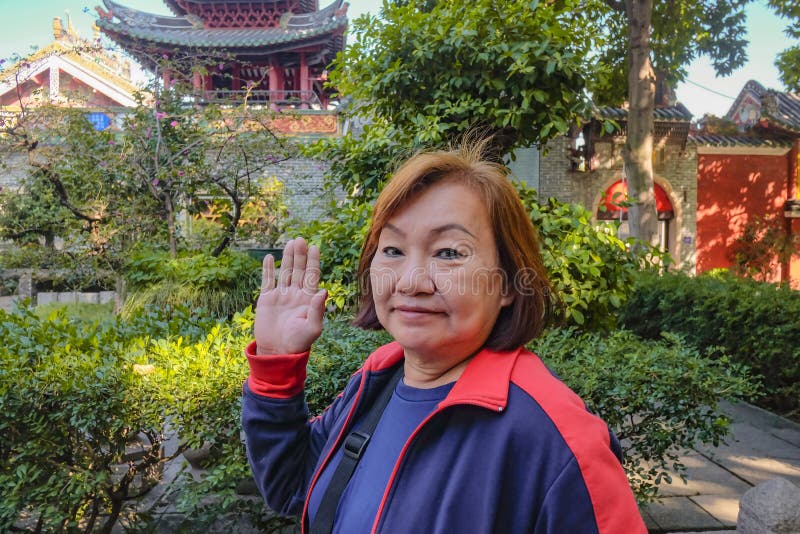 Höga asiatiska turist- kvinnor som går stund, säger ’hi ’till kameran i den släkt- templet arkivbilder Höga asiatiska turist- kvinnor som går stund, säger ’hi ’till kameran i den släkt- templet arkivbilder