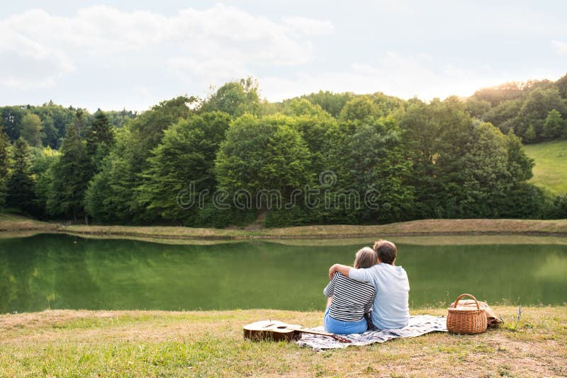 Höga par på sjön som har en picknick royaltyfri fotografi Höga par på sjön som har en picknick royaltyfri fotografi