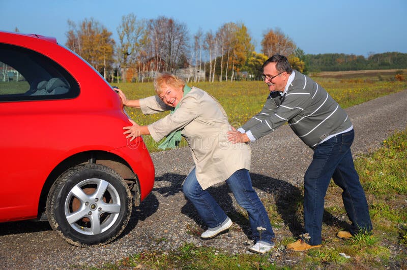 Höga par skjuter den broken bilen arkivbild Höga par skjuter den broken bilen arkivbild