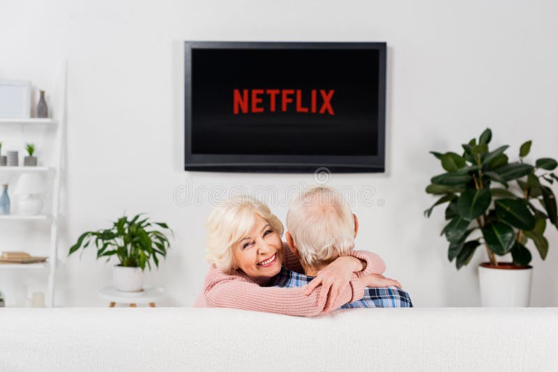 höga par som framme omfamnar på soffan av tv med netflixlogo arkivfoton höga par som framme omfamnar på soffan av tv med netflixlogo arkivfoton