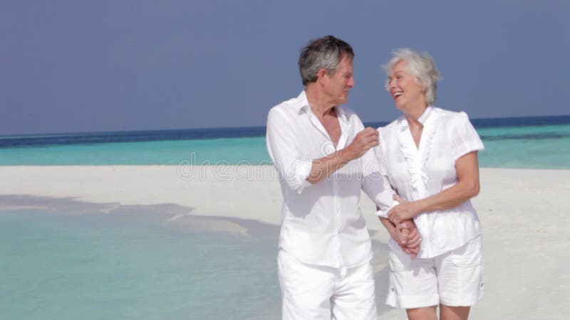 Höga par som går på den härliga stranden arkivfilmer