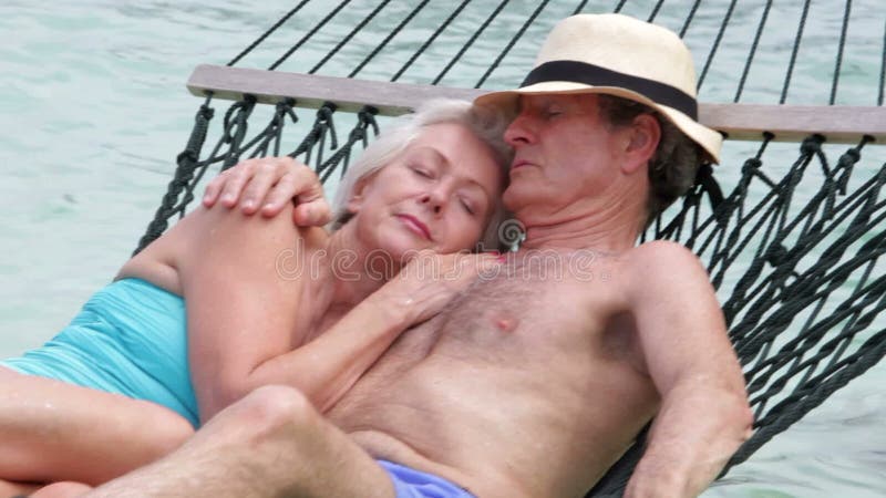 Höga par som kopplar av i strandhängmatta lager videofilmer
