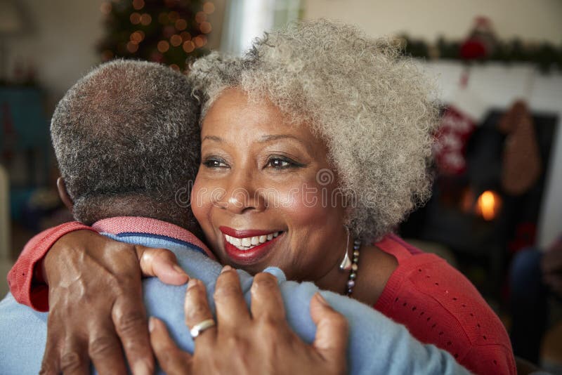 Senior Couple Hugging As They Celebrate Christmas At Home Together. Senior Couple Hugging As They Celebrate Christmas At Home Together