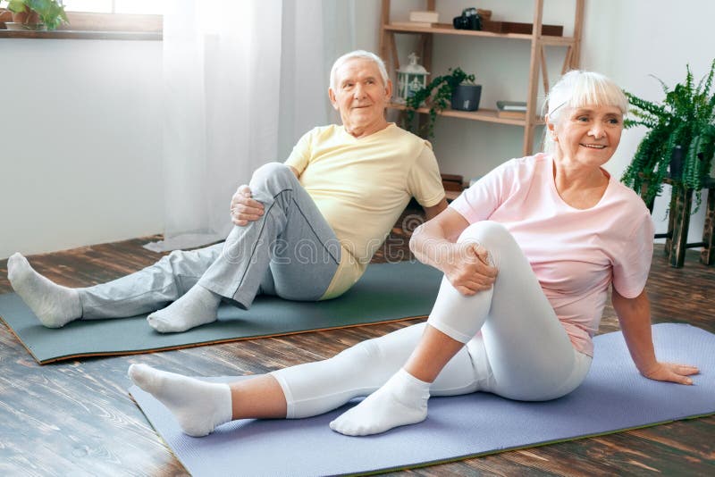 Höga par som tillsammans gör för hälsovårdben för yoga hemmastadd sträckning royaltyfria bilder Höga par som tillsammans gör för hälsovårdben för yoga hemmastadd sträckning royaltyfria bilder