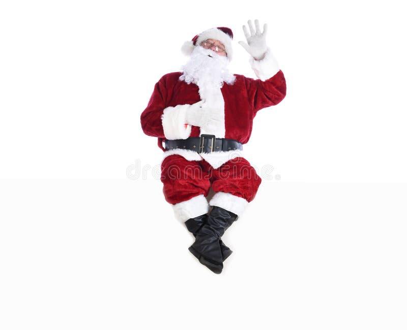 Högre man i den traditionella juldräkten som sitter på en vit vägg med ena handen i luften och den andra på sin mage och hans mage