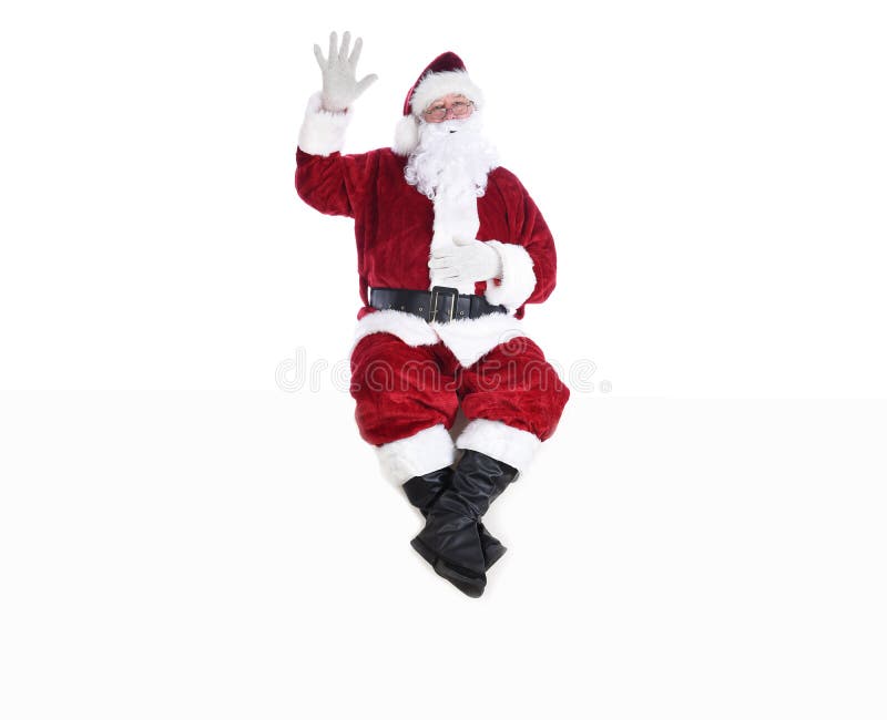 Högre man i den traditionella juldräkten som sitter på en vit vägg med ena handen i luften och den andra på sin mage och hans mage