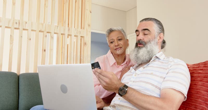 Högre par som använder bärbara datorer och som har kreditkortsshopping online tillsammans lager videofilmer