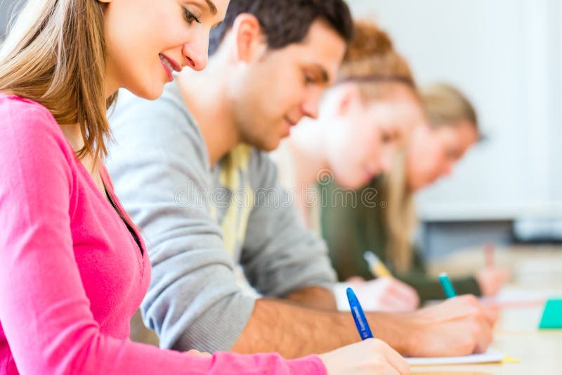 Högskolestudenter som skriver provet eller examen royaltyfri fotografi Högskolestudenter som skriver provet eller examen royaltyfri fotografi