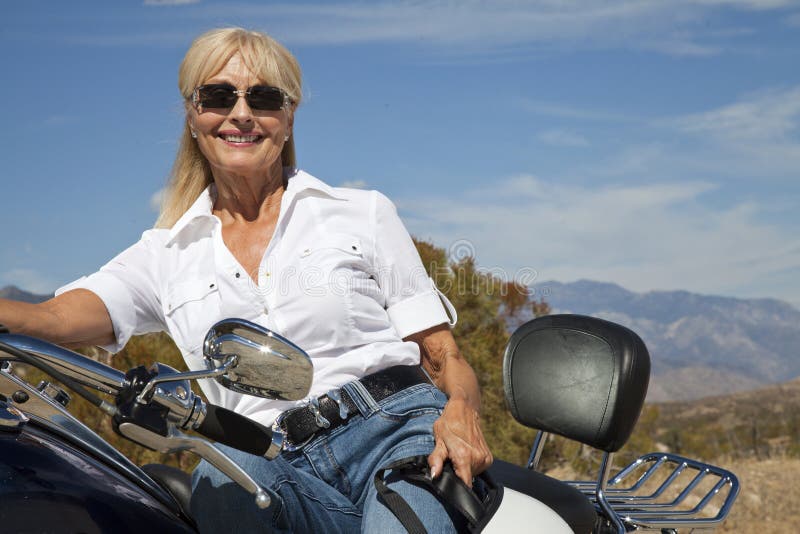 Senior women sitting on motorcycle on desert road. Senior women sitting on motorcycle on desert road