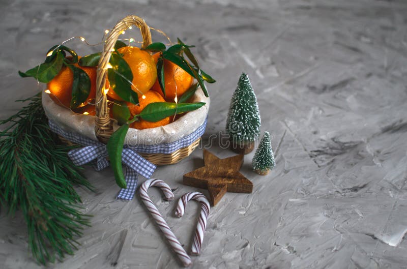 Hölzerne Korb-Mandarine mit Blättern und Lichtern, Tangerine-Orange auf Gray Table Background Christmas New-Jahr-Dekors lizenzfreie stockbilder Hölzerne Korb-Mandarine mit Blättern und Lichtern, Tangerine-Orange auf Gray Table Background Christmas New-Jahr-Dekors lizenzfreie stockbilder