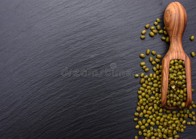 Hölzerne Schaufel der Bohnen auf dem Hintergrund eines schwarzen Steinbrettes, Platz für Text, Mungobohne lizenzfreie stockfotos Hölzerne Schaufel der Bohnen auf dem Hintergrund eines schwarzen Steinbrettes, Platz für Text, Mungobohne lizenzfreie stockfotos