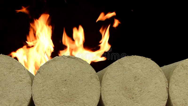 Hölzerne Sägemehlökobriketts richteten, brennendes Feuer des Hintergrundes auf Schnee im Winter gerade Alternativer Brennstoff, B