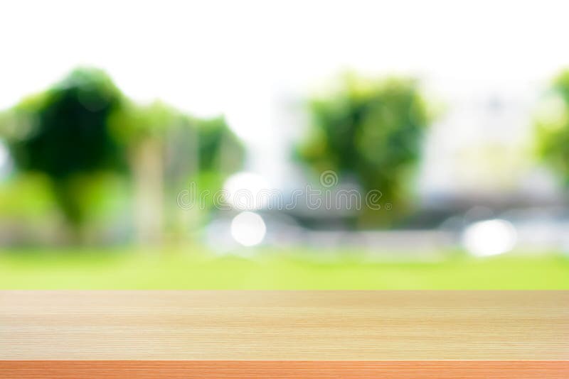 Hölzerne Tischplatte auf unscharfem grünem Naturzusammenfassungshintergrund
