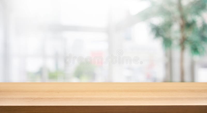 Hölzerne Tischplatte auf Unschärfeweißem Glaswandhintergrundformbürogebäude