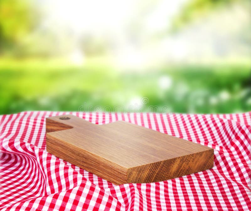 Hölzernes leeres Brett über Picknickstoff auf einem Gras lizenzfreie stockfotos Hölzernes leeres Brett über Picknickstoff auf einem Gras lizenzfreie stockfotos