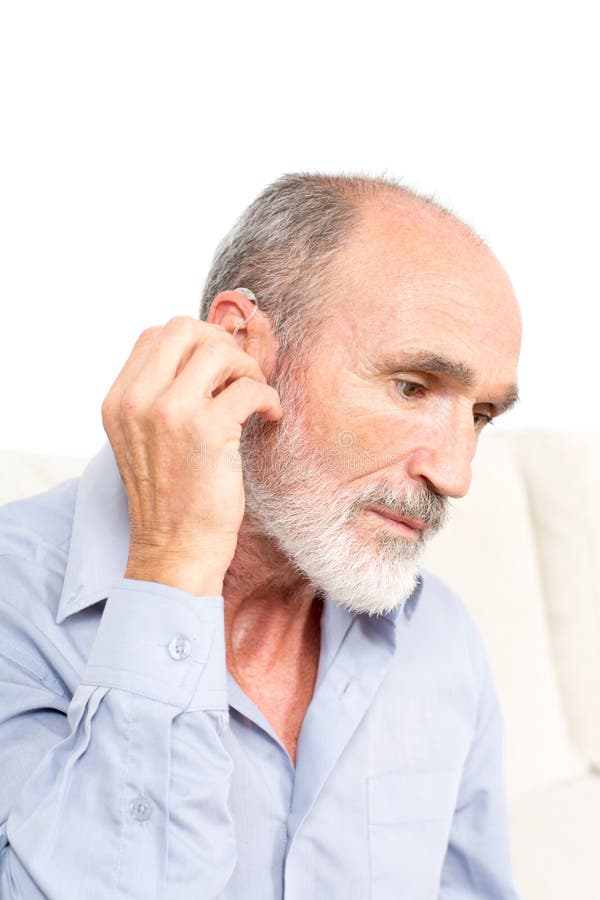 Elderly man putting some hearing aid in his ear. Elderly man putting some hearing aid in his ear