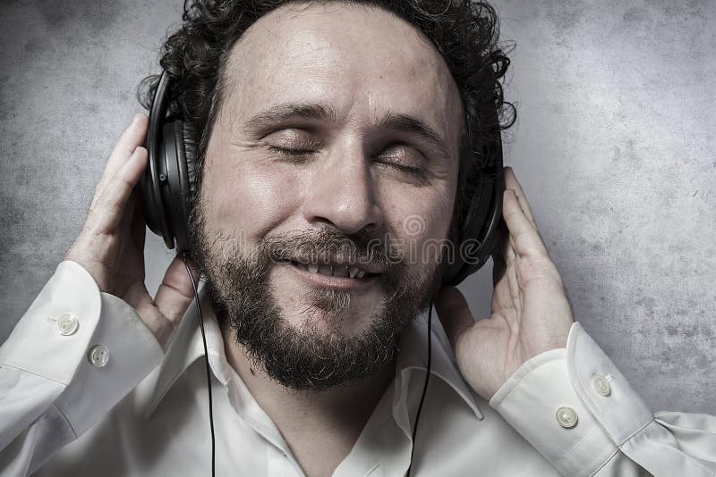 Listening and enjoying music with headphones, man in white shirt with funny expressions. Listening and enjoying music with headphones, man in white shirt with funny expressions