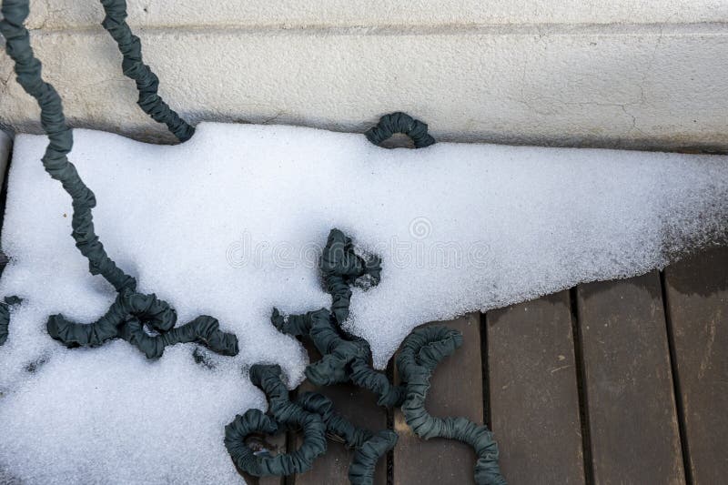 Corner of a terrace with accumulated ice and an elastic hose between. Corner of a terrace with accumulated ice and an elastic hose between