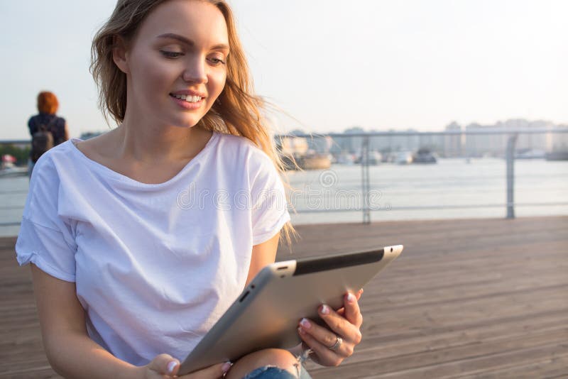 Hübsch lächelnde Frau über das soziale Netzwerk über Touchpad während der Pause in der frischen Luft lizenzfreies stockfoto