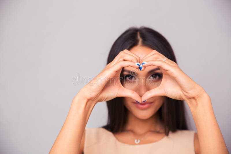 Hübsche Frau, die Herz mit den Fingern macht lizenzfreie stockbilder Hübsche Frau, die Herz mit den Fingern macht lizenzfreie stockbilder
