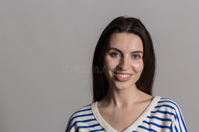Hübsche Frau mit dem flaumigen Haar, zufällig gekleidet gegen eine graue Studiowand stockfotografie Hübsche Frau mit dem flaumigen Haar, zufällig gekleidet gegen eine graue Studiowand stockfotografie