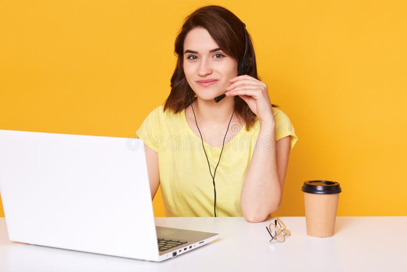 Hübsche Frau sitzt am weißen Schreibtisch mit geöffneter Laptop-Computer, schreibt E-Mail, benutzt das Hochgeschwindigkeitsintern stockbild