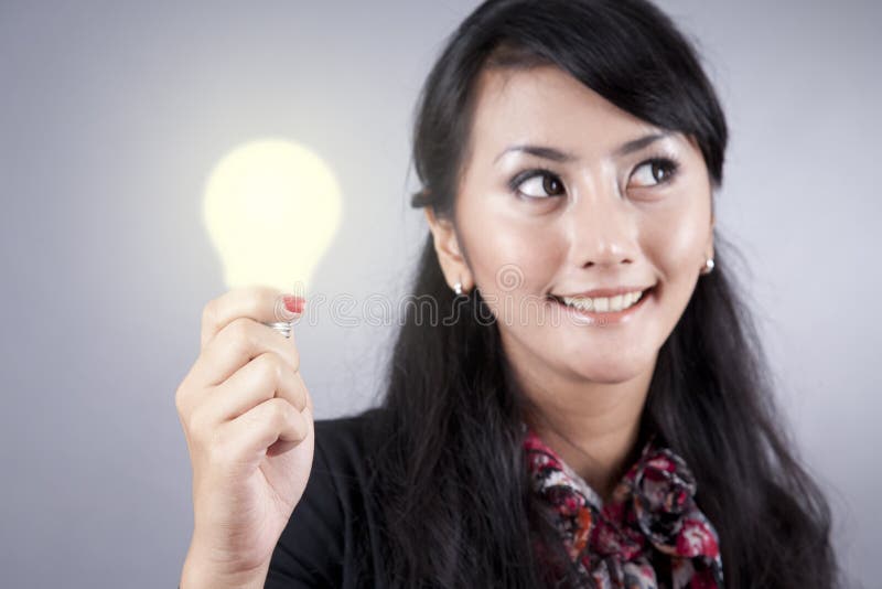 Hübsche Geschäftsfrau hält eine Glühlampe an lizenzfreie stockfotografie Hübsche Geschäftsfrau hält eine Glühlampe an lizenzfreie stockfotografie